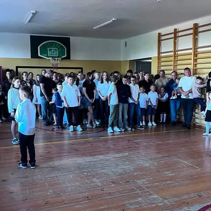 Uczniowie i rodzice zgromadzeni w sali gimnastycznej podczas rozpoczęcia roku szkolnego
